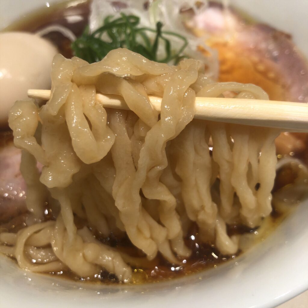 平打ち縮れ麺。艶やかな表面がスープをしっかりまとっている