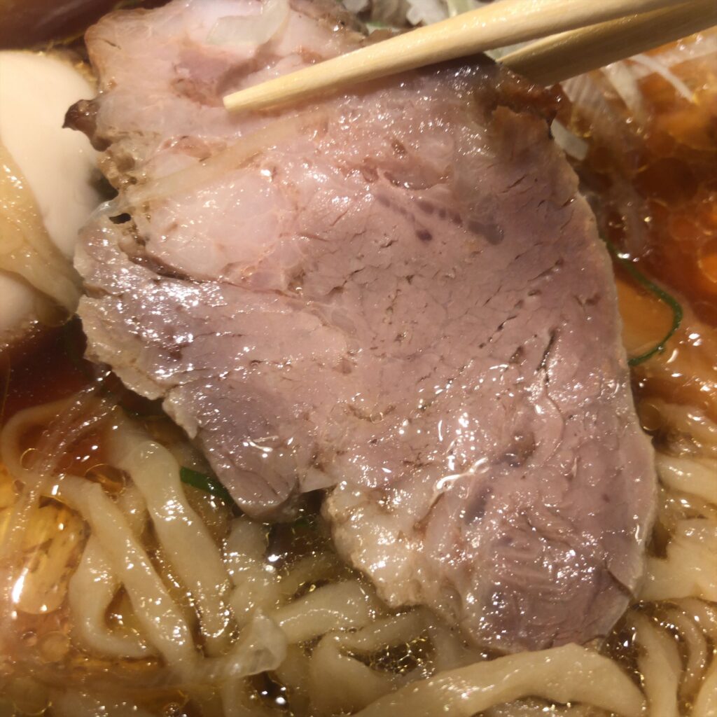 豚肩ロースチャーシューのアップ。下には手もみ麺と澄んだスープ