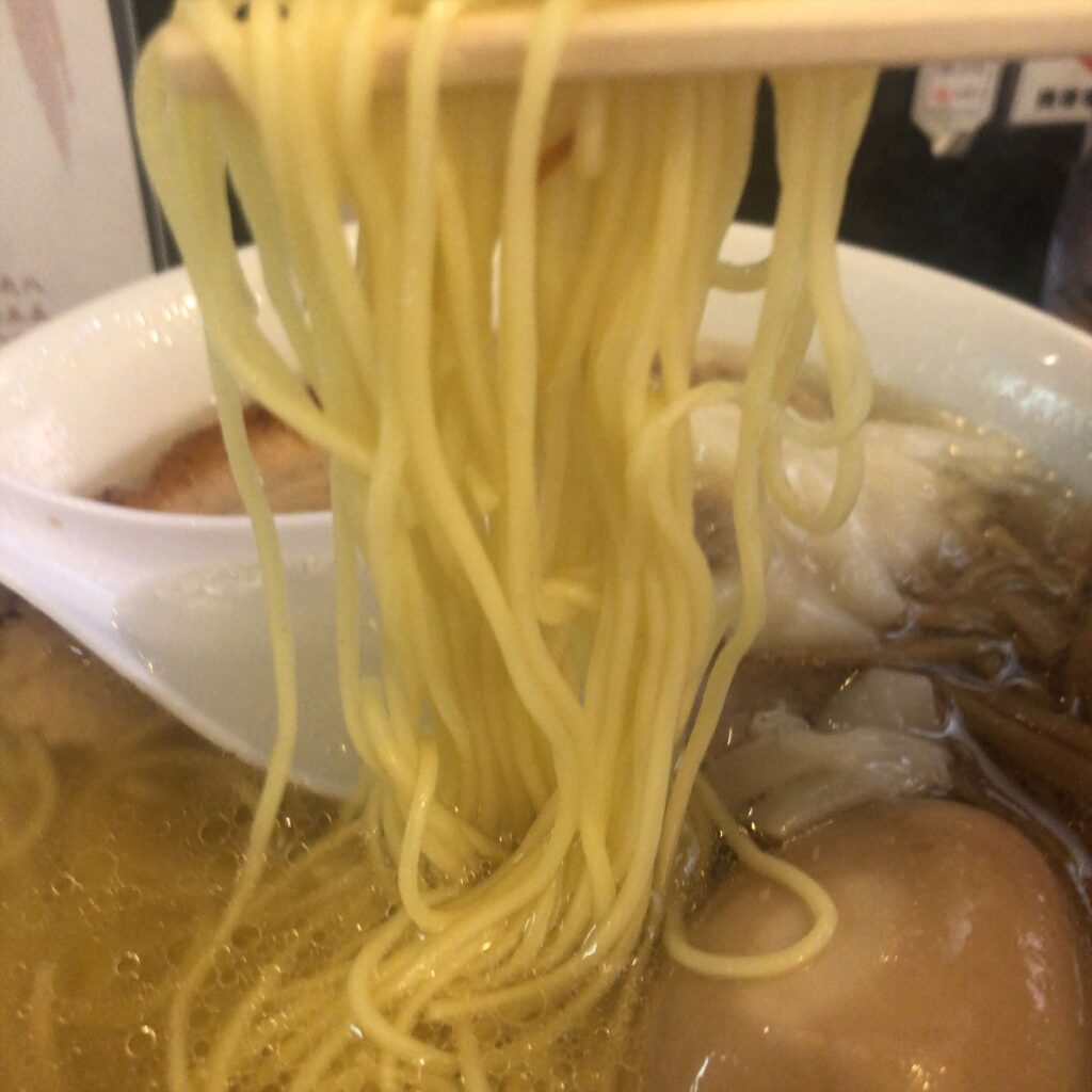 塩そば専門店 桑ばらの特製塩そばから持ち上げた極細ストレート麺。透明なスープが絡む一口。