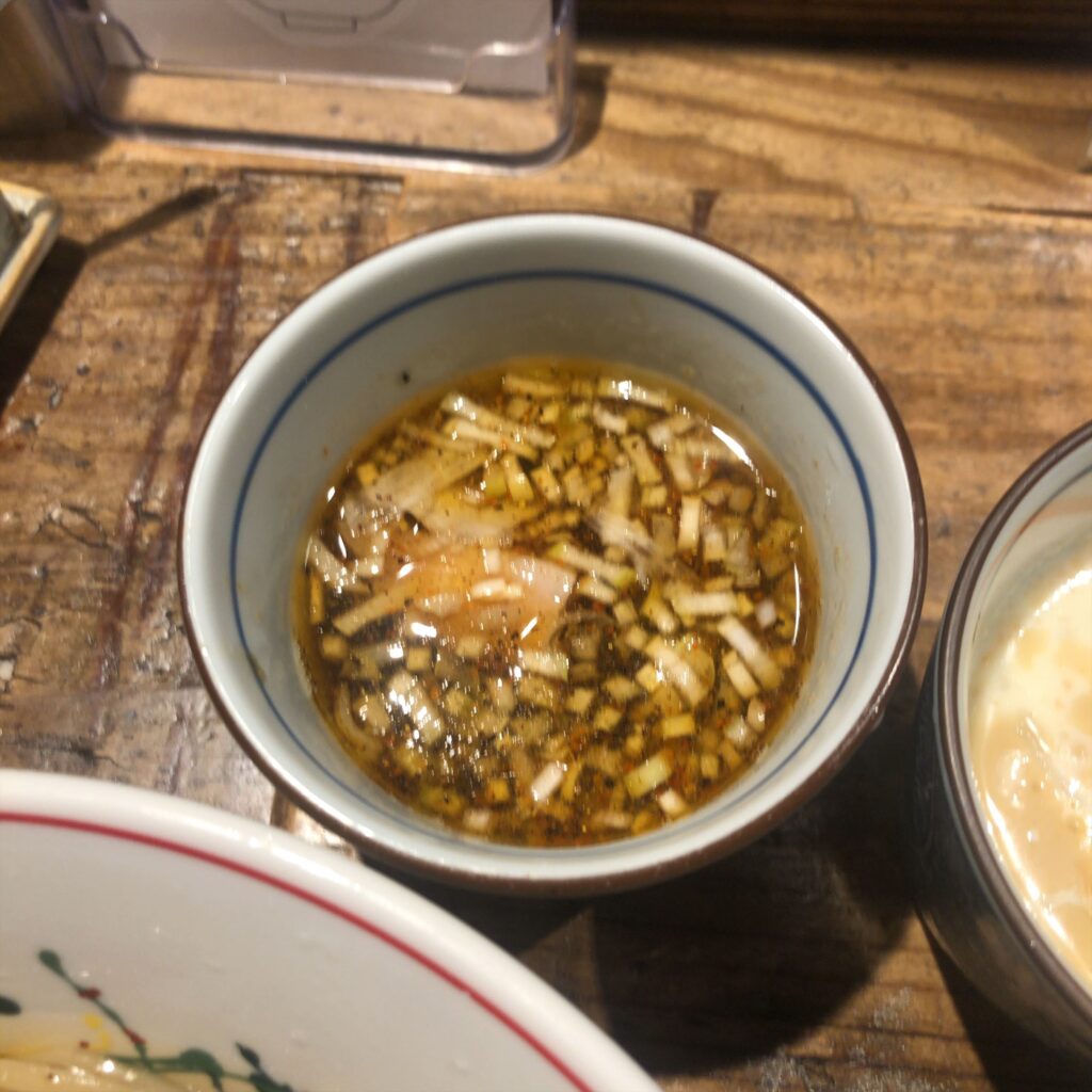 伊之瀬のつけ汁「東京クラシック」。刻みネギが浮かぶ、醤油ベースの王道甘じょっぱいスープ。