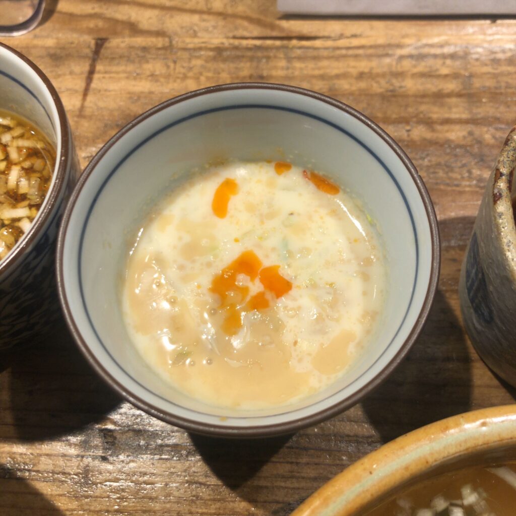 伊之瀬の味変スープ「冷やし豆乳担担」。白くまろやかな豆乳スープにラー油が浮かぶ冷製つけ汁。