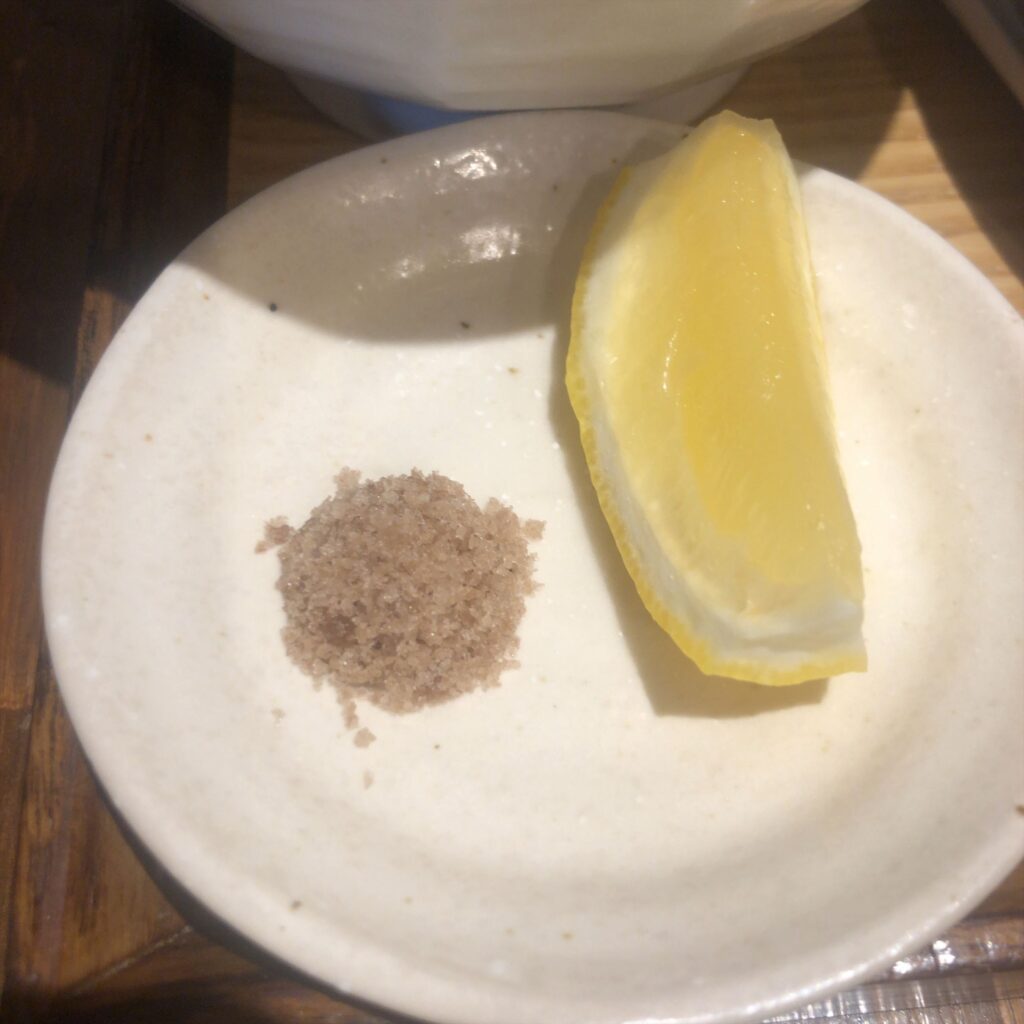 麺屋鈴春の昆布水つけ麺に添えられた藻塩とレモン。白い皿の上に、小さく盛られた藻塩とレモンが並んでいる。