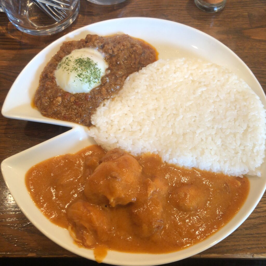 キーマカレーとチキンカレーの2種盛り「みのりんごスペシャル」。中央にライス、キーマには半熟卵、チキンカレーには大きめの鶏肉が入った一皿。