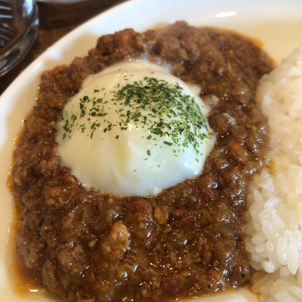 スパイスの効いたキーマカレーに温泉卵をのせた一皿。粗挽き肉の食感と、とろりとした卵黄が合わさる瞬間。