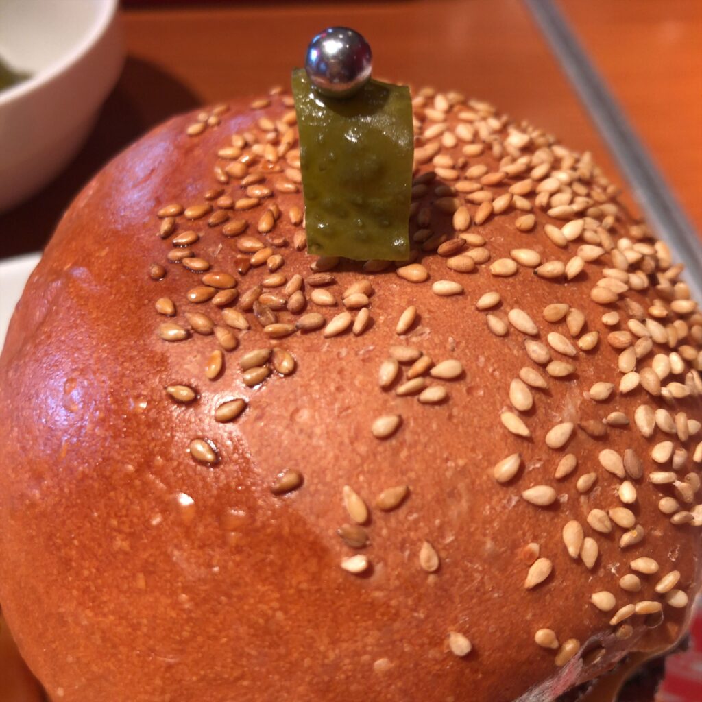 ごま付きバンズの上にピクルスが乗ったハンバーガー